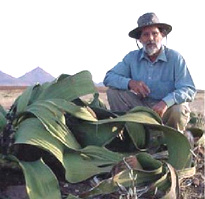 Colin R. Owen sitting next to a large desert plant